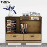 A promotional image of the "RETRO Mini Bookshelf," a compact, modern storage unit. The bookshelf has a light wood grain finish with contrasting black trim. It features two drawers at the bottom and an asymmetrical arrangement of open shelving above for books. The top surface is multi-leveled and is styled with a small vase of flowers and a stack of books. The "BONGO" and "RETRO" brand names are displayed in the top corners.